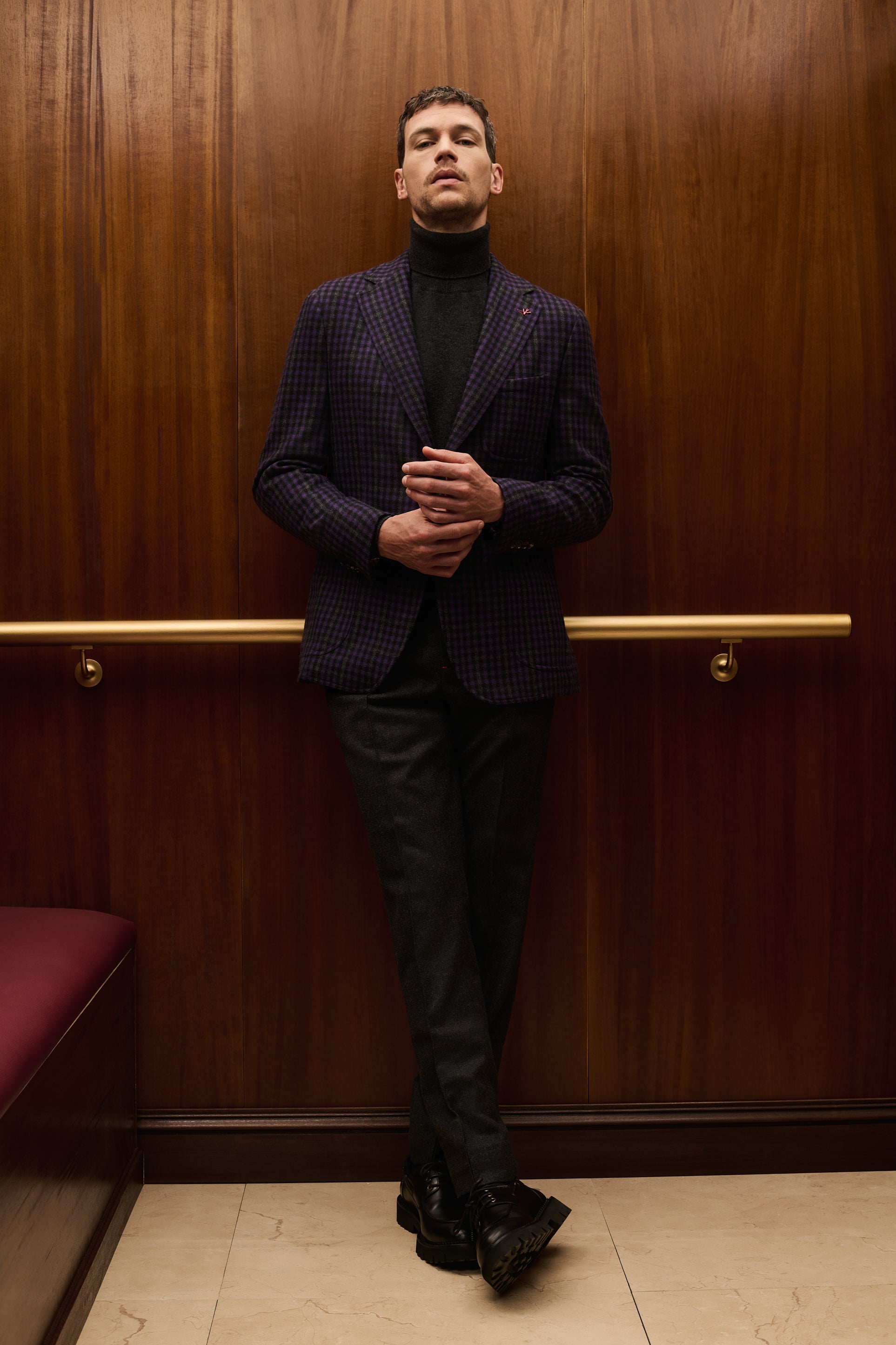 ISAIA Made to Measure: purple check jacket with black rollneck and grey trousers, legs crossed