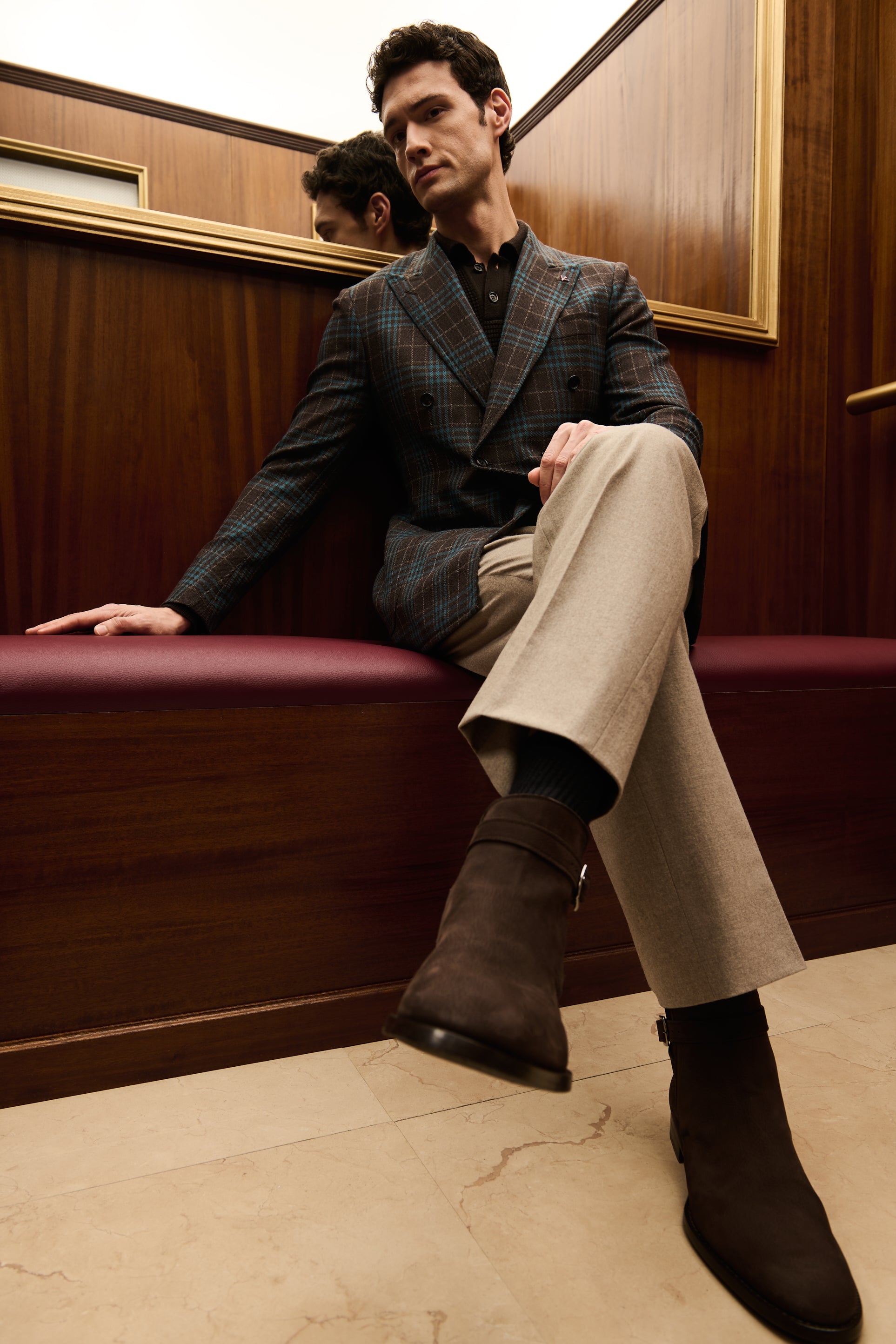 ISAIA Made to Measure: teal check double-breasted jacket and cream trousers, seated on the elevator bench
