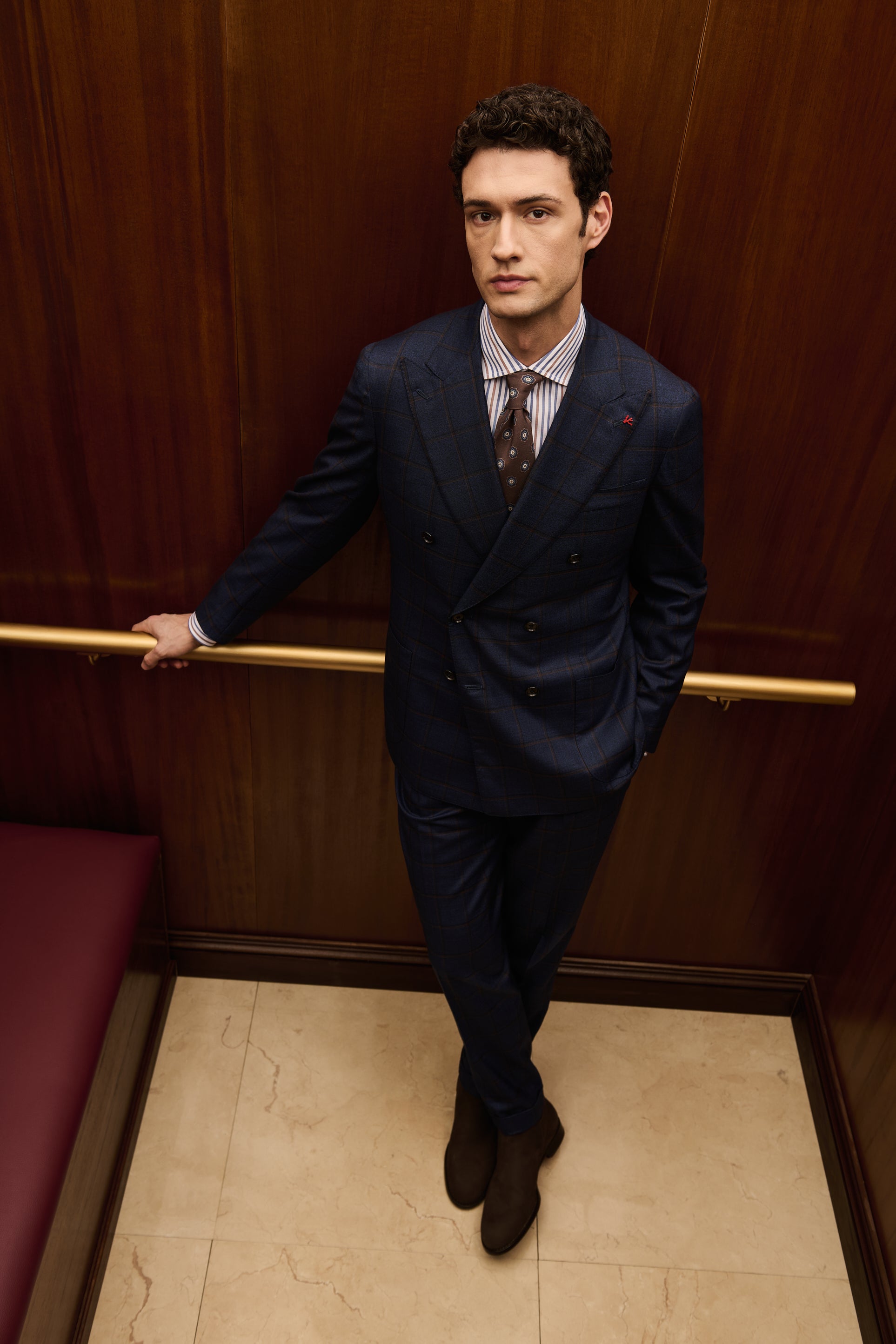 ISAIA Made to Measure: navy double-breasted suit with striped shirt and patterned tie, legs crossed