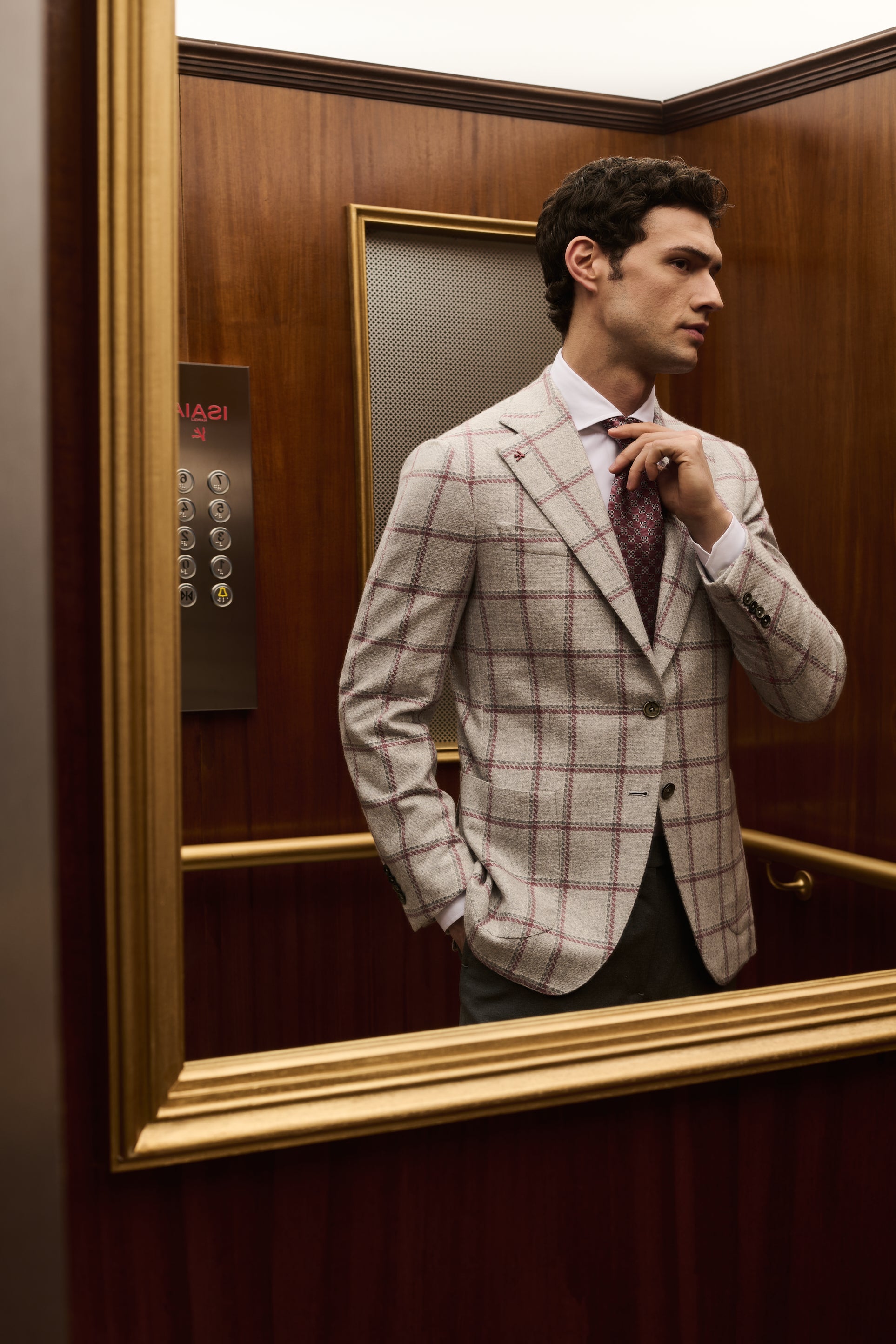 ISAIA Made to Measure: ivory windowpane check jacket with burgundy tie, reflected in the elevator mirror